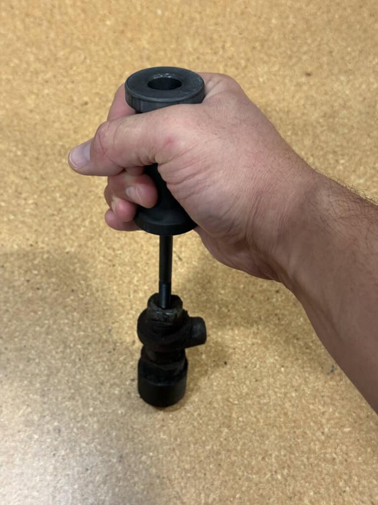 slide hammer with Yanmar 2QM20 injection valve held above on particle board